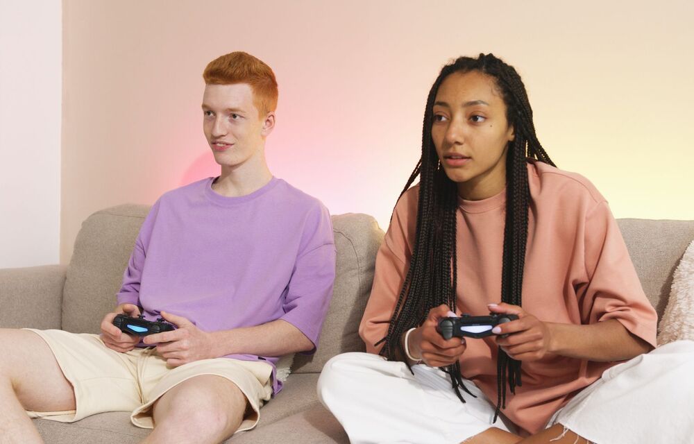 Two friends gaming together on the sofa